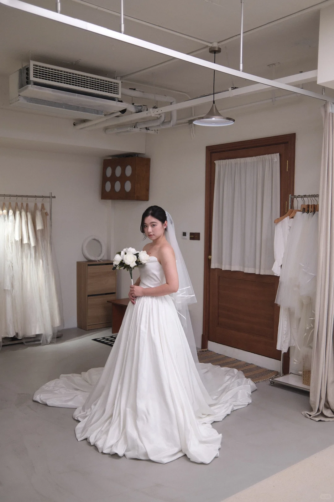 For that day 上海门店内，手捧花束的新娘试穿缎面拖尾婚纱